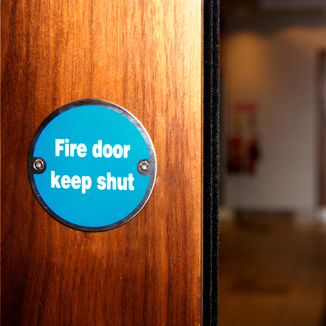 Close-up shot of fire door with blue metal warning sign.
