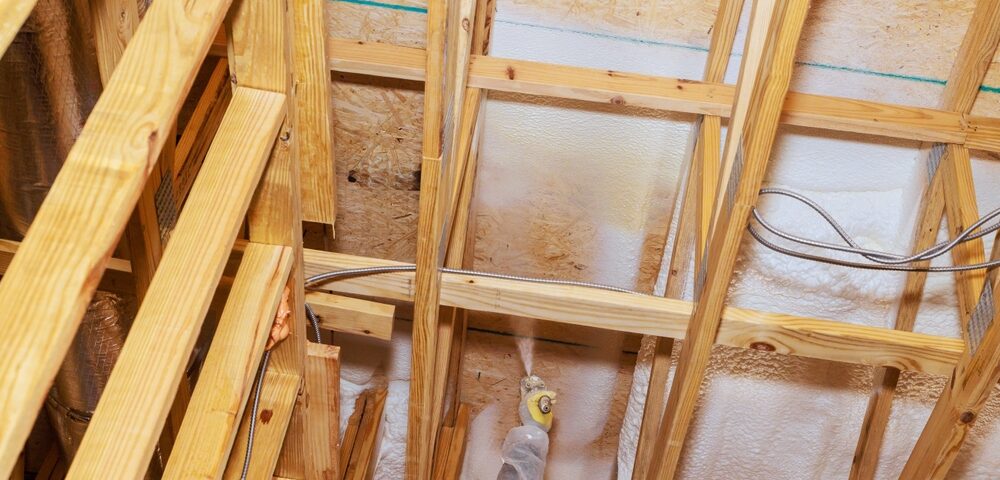 A worker installing spray foam insulation on a ceiling